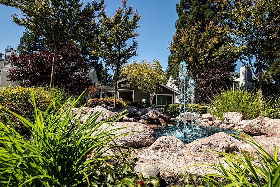 a water fountain in a rock garden in front of a house