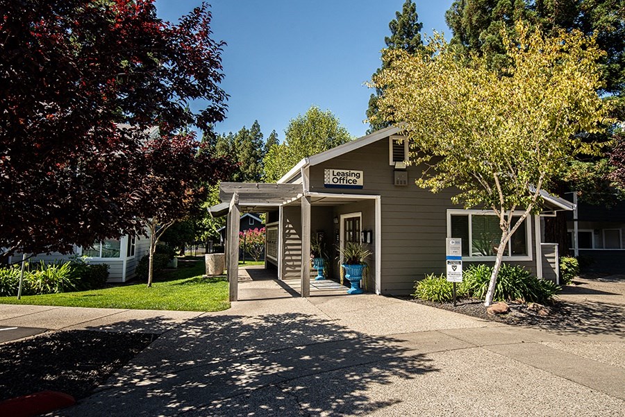 a small gray building with a porch and a sign on it