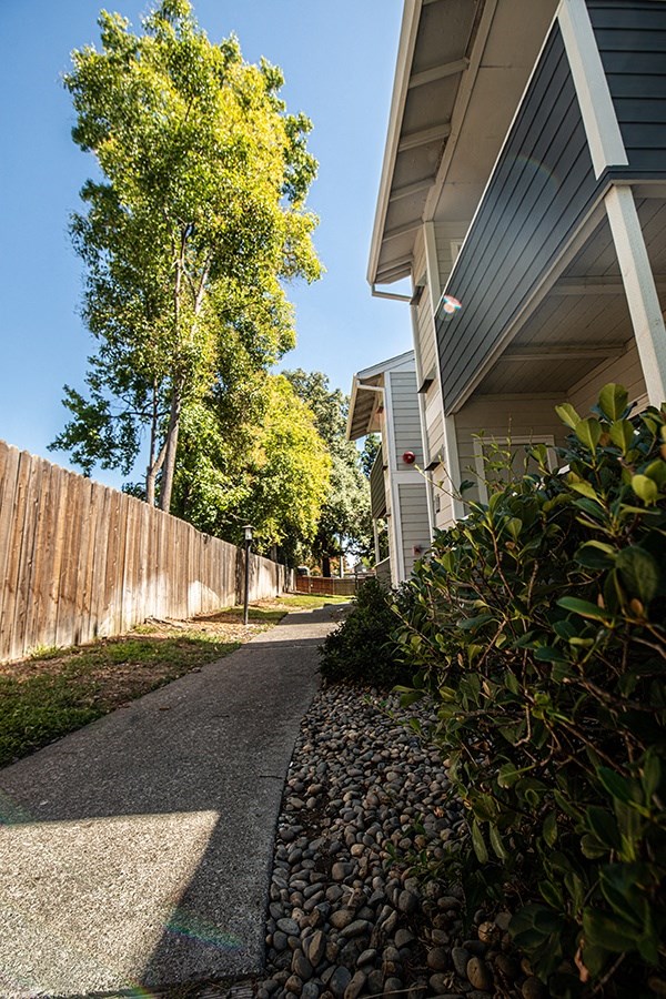 a sidewalk in front of a house next to a fence