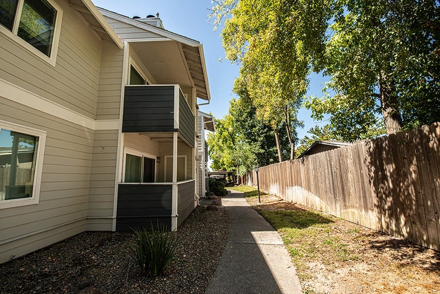 a sidewalk in front of a house next to a wooden fence