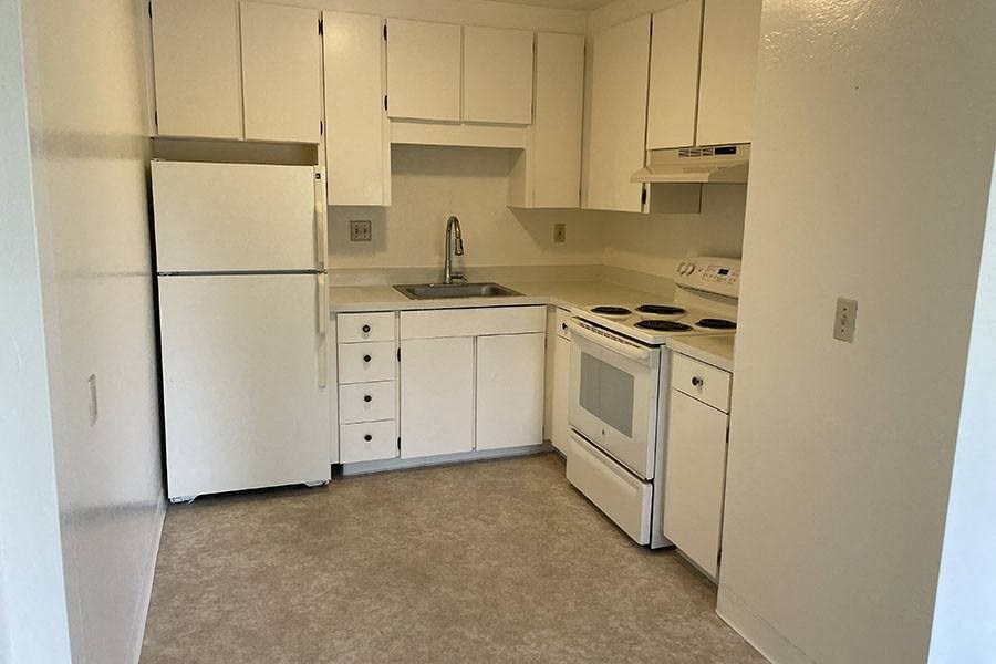 a kitchen with a white refrigerator freezer and a stove top oven a kitchen with a white refrigerator freezer and a stove top oven at OTAVON APARTMENTS, California, 94947