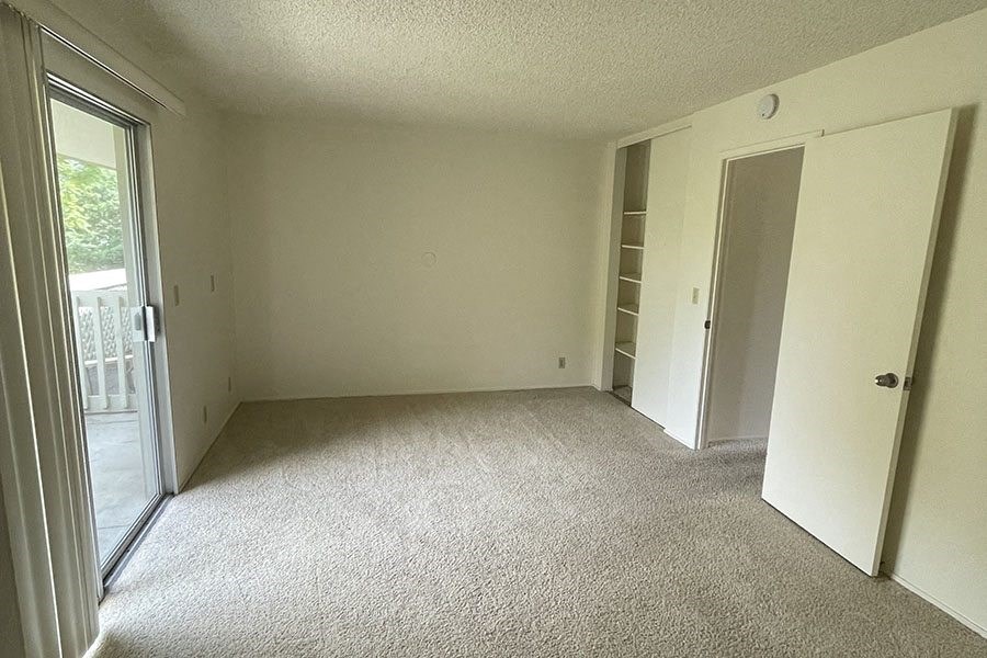 an empty room with a sliding glass door and a door to a balcony