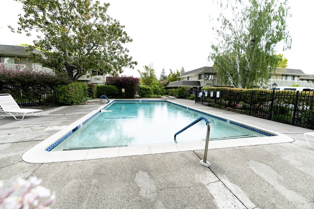 a swimming pool with a fence and trees in the background