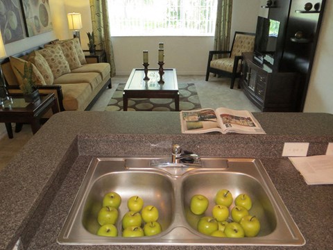 a sink filled with apples in a kitchen with a living room