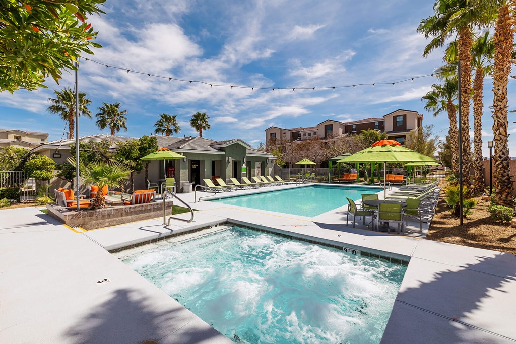 a swimming pool with chairs and umbrellas and a house in the background at EVERETT APARTMENT HOMES, Nevada