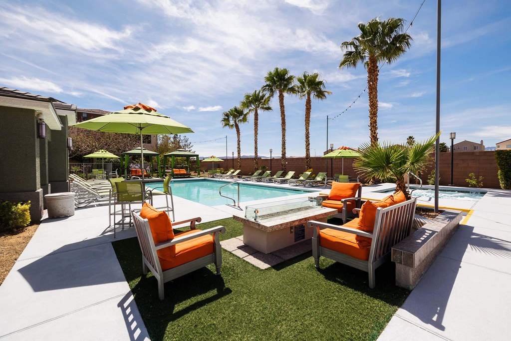 a pool with chairs and umbrellas next to a resort style pool at EVERETT APARTMENT HOMES, Las Vegas, NV