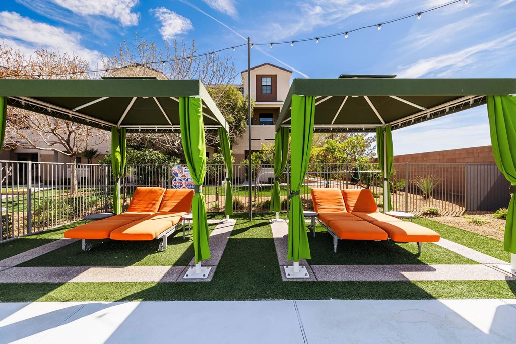 a lounge area with orange lounge chairs and green umbrellas at EVERETT APARTMENT HOMES, Nevada, 89113