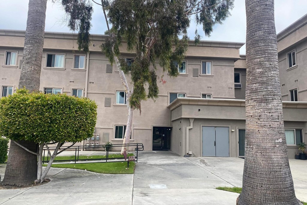 an apartment building with a sidewalk and palm trees