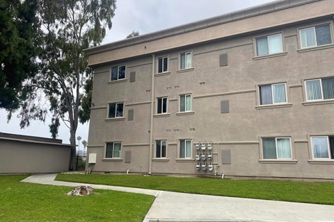 the side of a building with grass and a sidewalk
