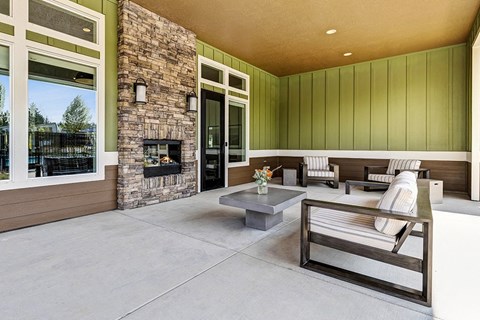 A modern outdoor living space with a stone fireplace and seating area at View by Vintage Apartments, Bonney Lake