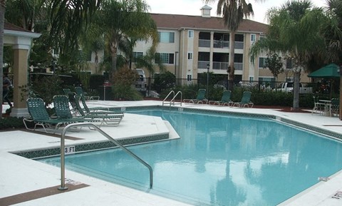 a swimming pool with chairs and a building in the background