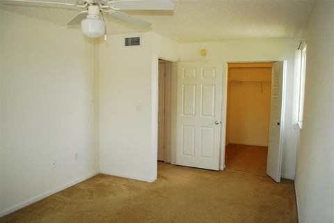 an empty living room with a ceiling fan and a closet