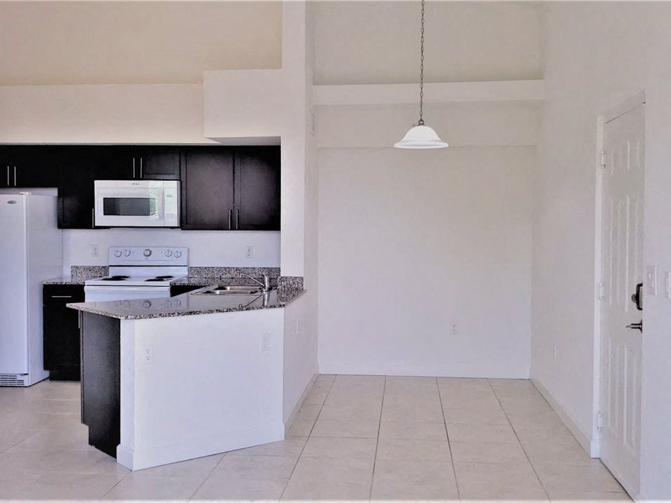 Mirabella Apartments kitchen area with white appliances and bar top for seating plus dining space at Mirabella Apartments, Princeton, FL