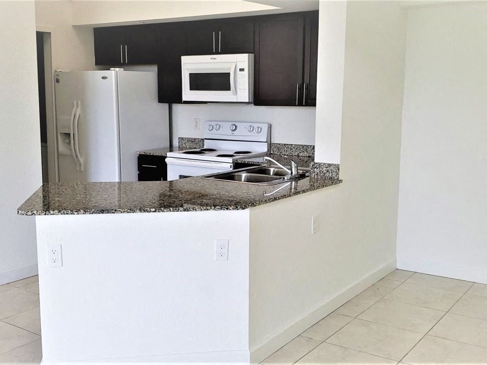 Mirabella Apartments kitchen area with white appliances and bar top for seating at Mirabella Apartments, Florida