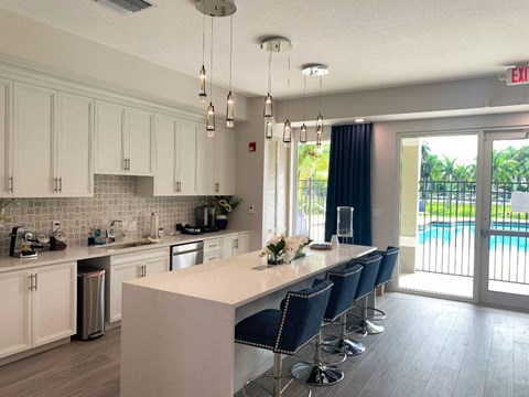 a kitchen with a long counter and chairs and a sliding glass door