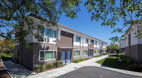 a row of buildings with blue and white doors and a sidewalk