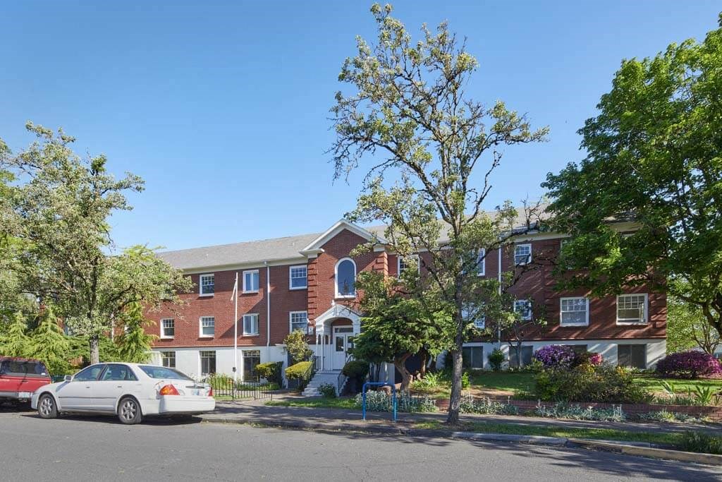 a white car parked in front of a red brick apartment building at MILEPOST 5 Apartments, PORTLAND, OR