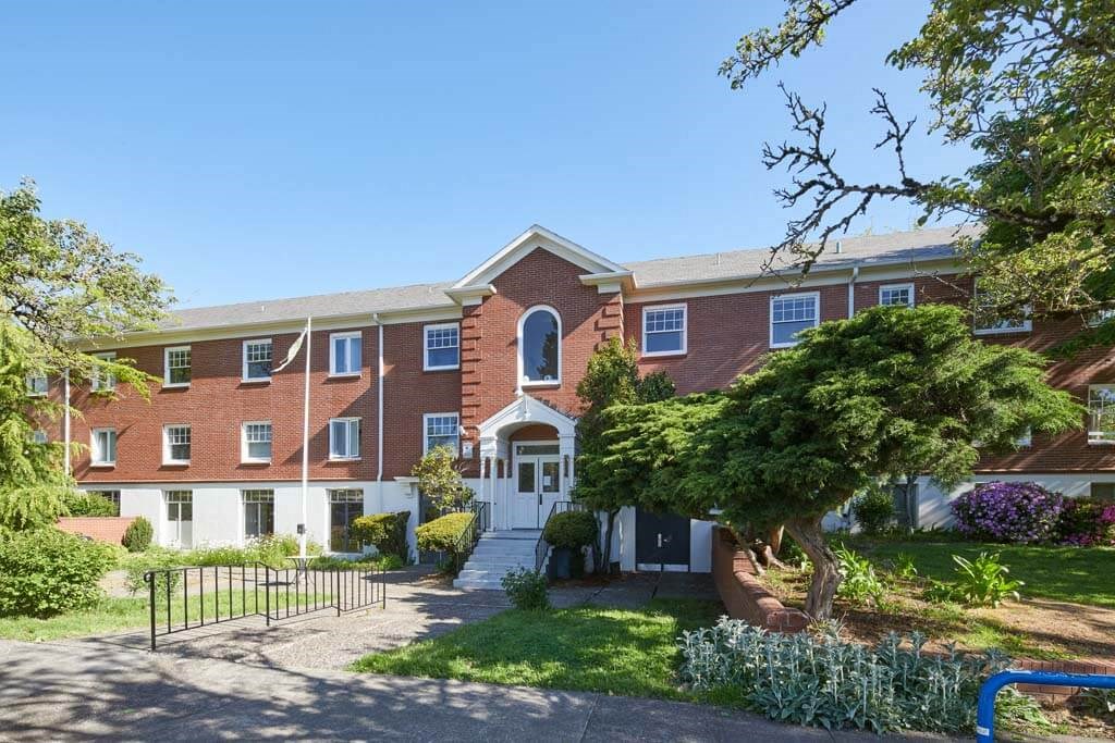 a large brick building with a tree in front of it at MILEPOST 5 Apartments, PORTLAND, 97213