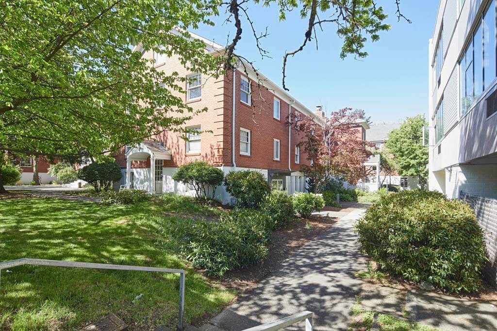 a brick building with a white fence in front of it at MILEPOST 5 Apartments, PORTLAND, 97213