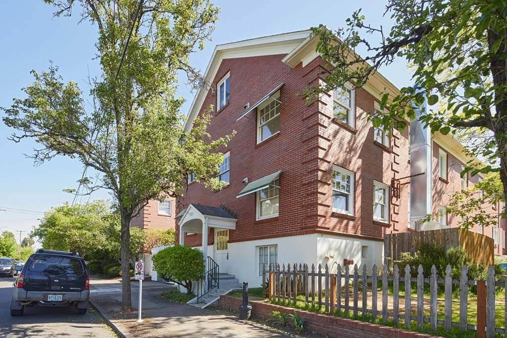 a red brick apartment building with a car parked in front of it 1 at MILEPOST 5 Apartments, PORTLAND