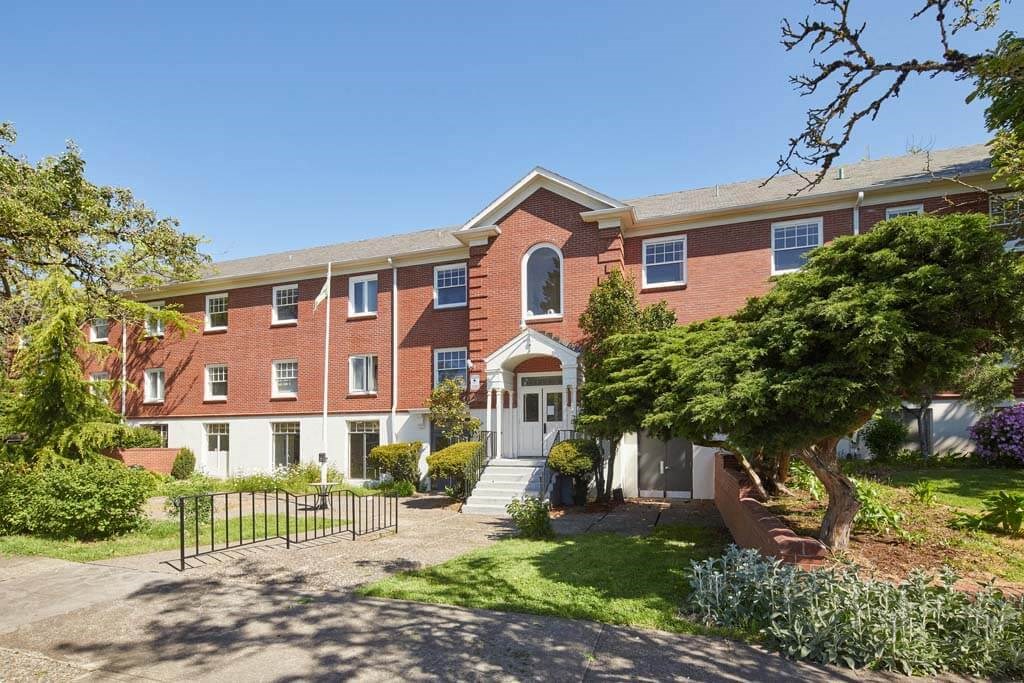 a red brick building with a white door and a tree in front of it at MILEPOST 5 Apartments, PORTLAND Oregon