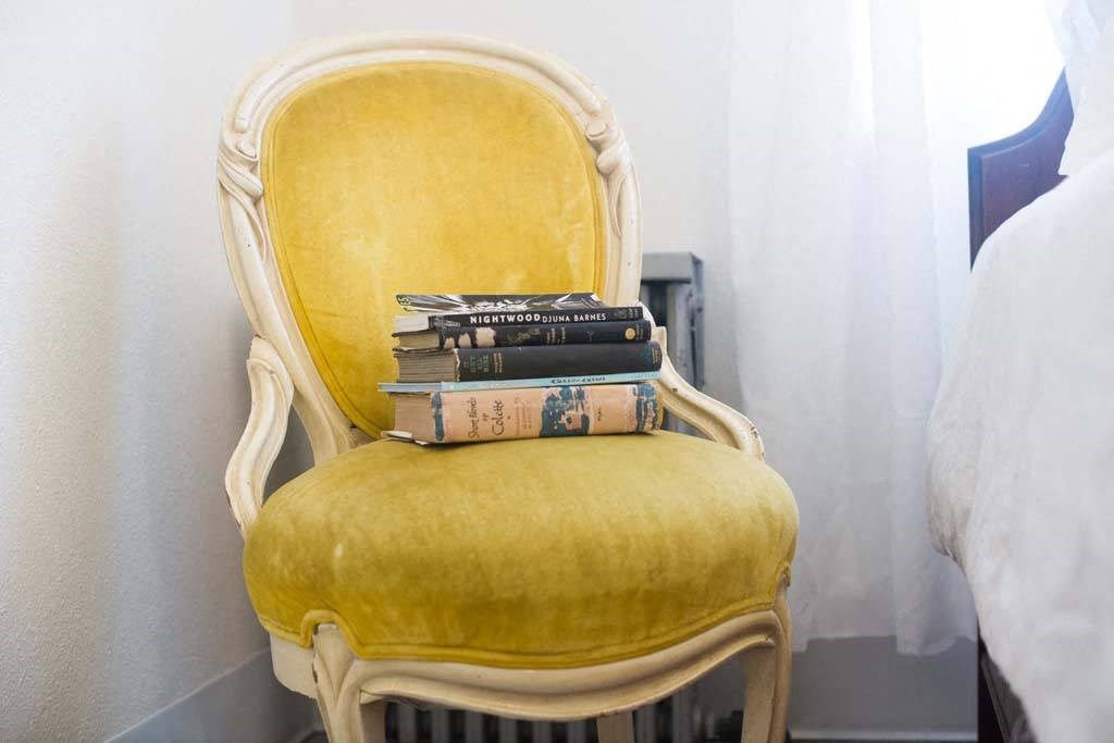 a yellow chair with a pile of books on it at MILEPOST 5 Apartments, PORTLAND