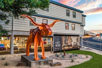 a large orange sculpture of a cow in front of a building at THE EASTWOOD, AUSTIN, TX 78705