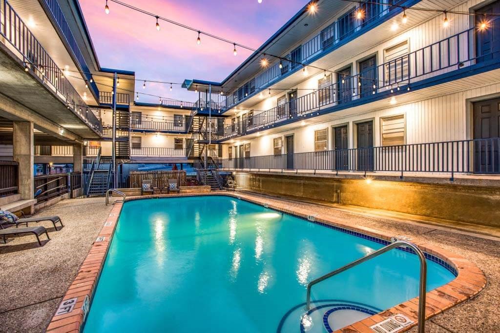 building with a pool and a purple sky in the background at THE EASTWOOD, AUSTIN, TX