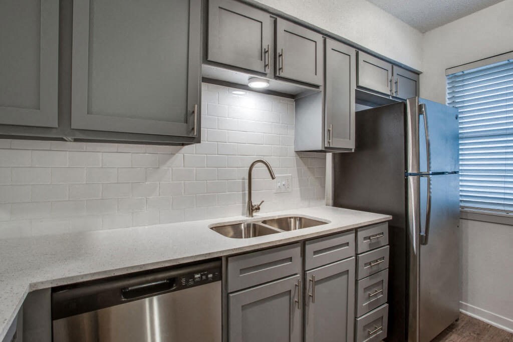 kitchen with gray cabinets and a stainless steel refrigerator at THE EASTWOOD, AUSTIN, TX