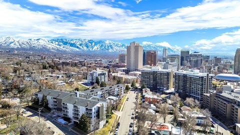 A cityscape with buildings and snow-capped mountains in the background.