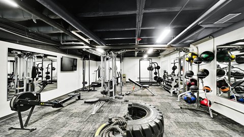 A gym with a variety of equipment including weights and a tire.