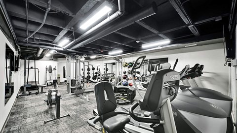 A gym with a variety of equipment including treadmills, weights, and exercise machines.