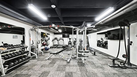 A black and white photo of a gym with various exercise equipment.
