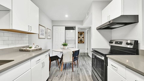 A modern kitchen with white cabinets and a black stove top oven.