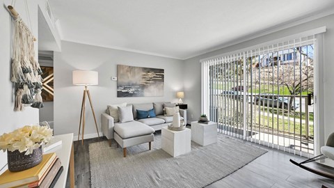 A living room with a white couch and a painting on the wall.