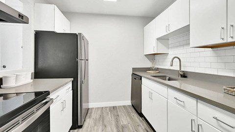 A kitchen with white cabinets and a black refrigerator.