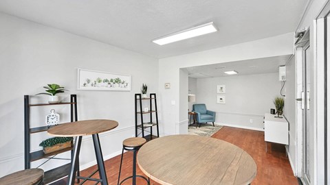 A room with a wooden table and chairs, a ladder, and a framed picture on the wall.