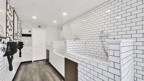 A bathroom with white tiles on the walls and a white sink.
