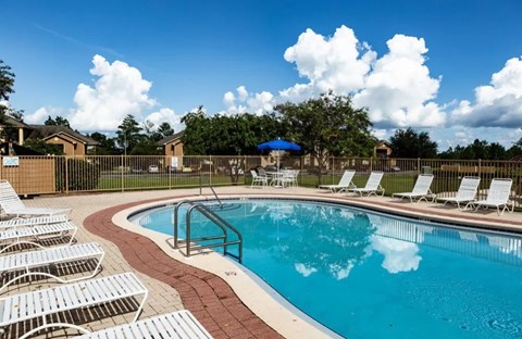 A pool surrounded by white chairs and a fence at ADDISON PLACE, CRESTVIEW