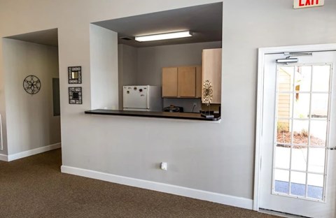 A kitchen area with a white fridge, cabinets, and a window.