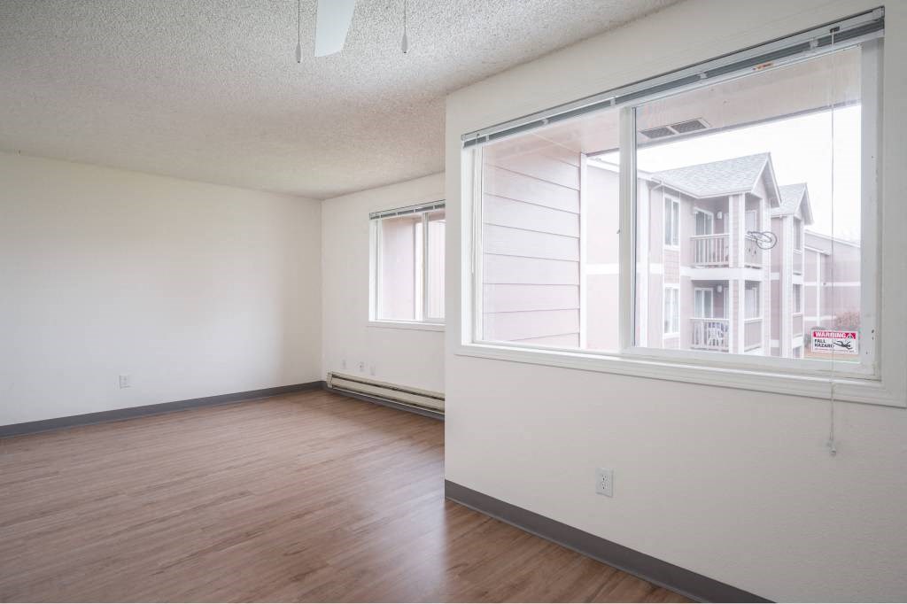 an empty living room with a large window and wood floors at Fort Vancouver Terrace, Washington