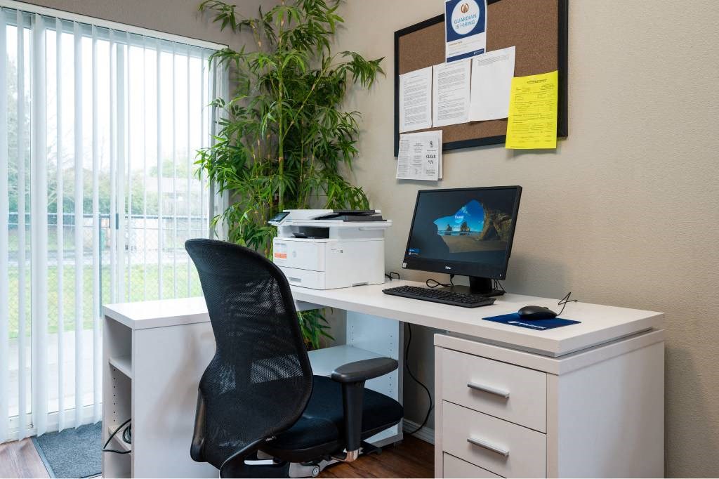 a desk with a computer and a chair in an office at Quail Run Apartments, Washington 98684