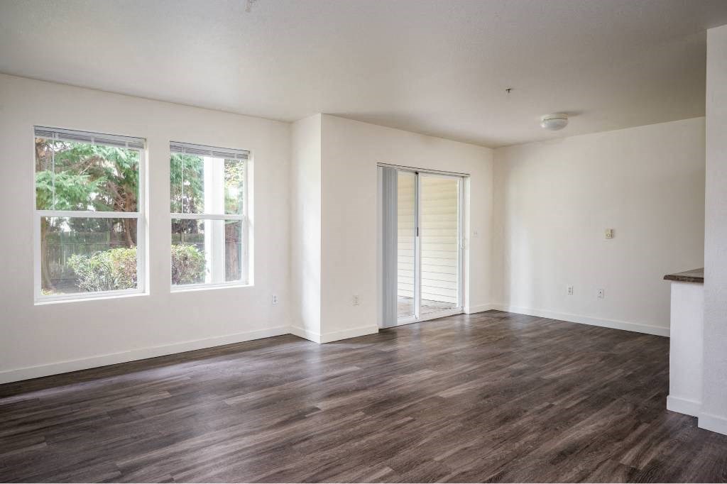 an empty living room with white walls and wood floors at Quail Run Apartments, Washington 98684