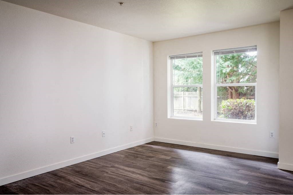 an empty room with white walls and a window at Quail Run Apartments, Vancouver