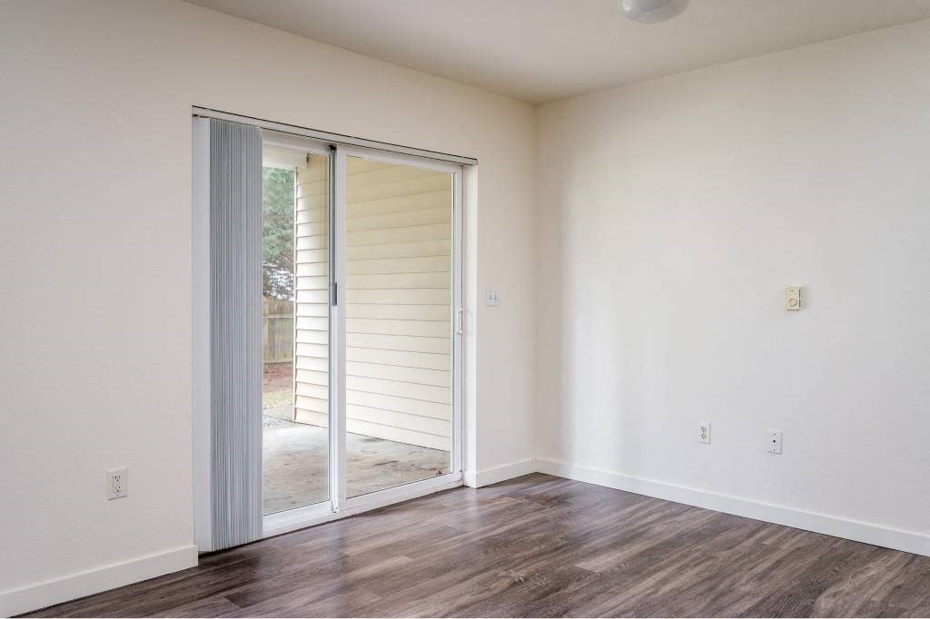 an empty living room with a sliding glass door to a patio at Quail Run Apartments, Vancouver, WA