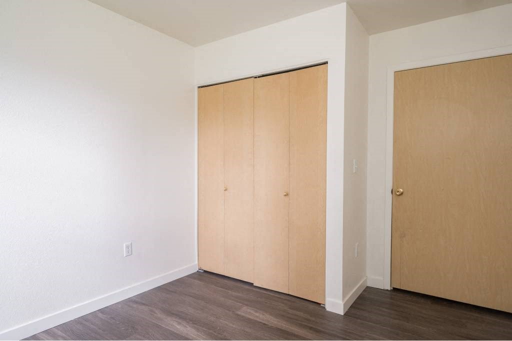 an empty room with white walls and wood floors and two closets at Quail Run Apartments, Vancouver, 98684