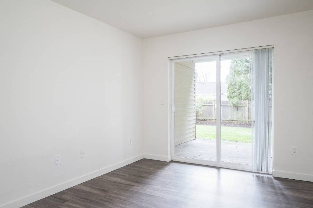 an empty living room with a sliding glass door to a yard at Quail Run Apartments, Vancouver, WA