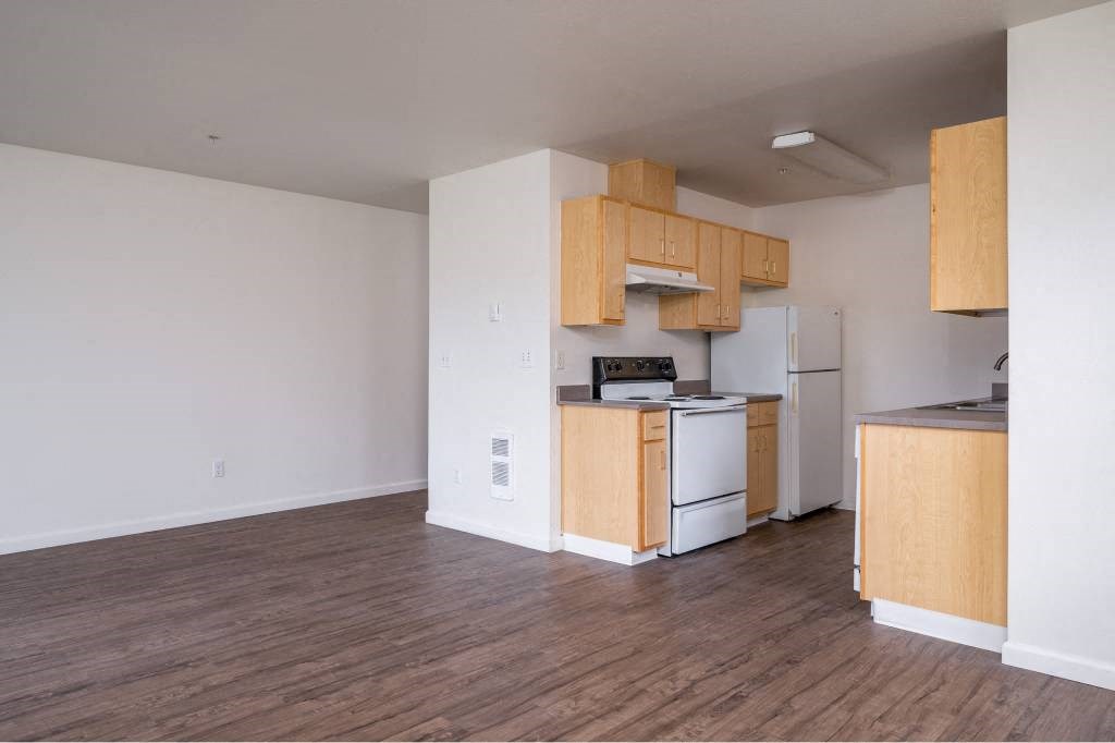 an empty kitchen with wooden cabinets and a white refrigerator at Quail Run Apartments, Washington 98684