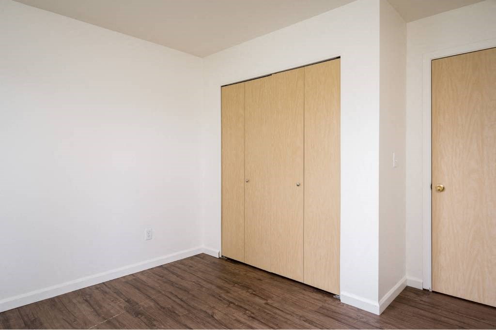 an empty room with white walls and wood floors and a closet at Quail Run Apartments, Vancouver, WA 98684