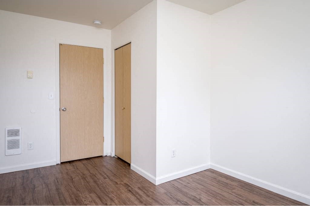 an empty room with white walls and wooden floors and two doors at Quail Run Apartments, Vancouver, Washington